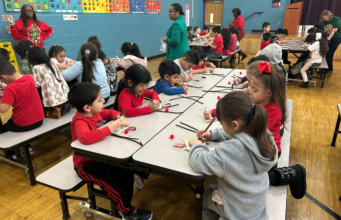 students sitting at cafeteria tables working on their reindeer ornaments